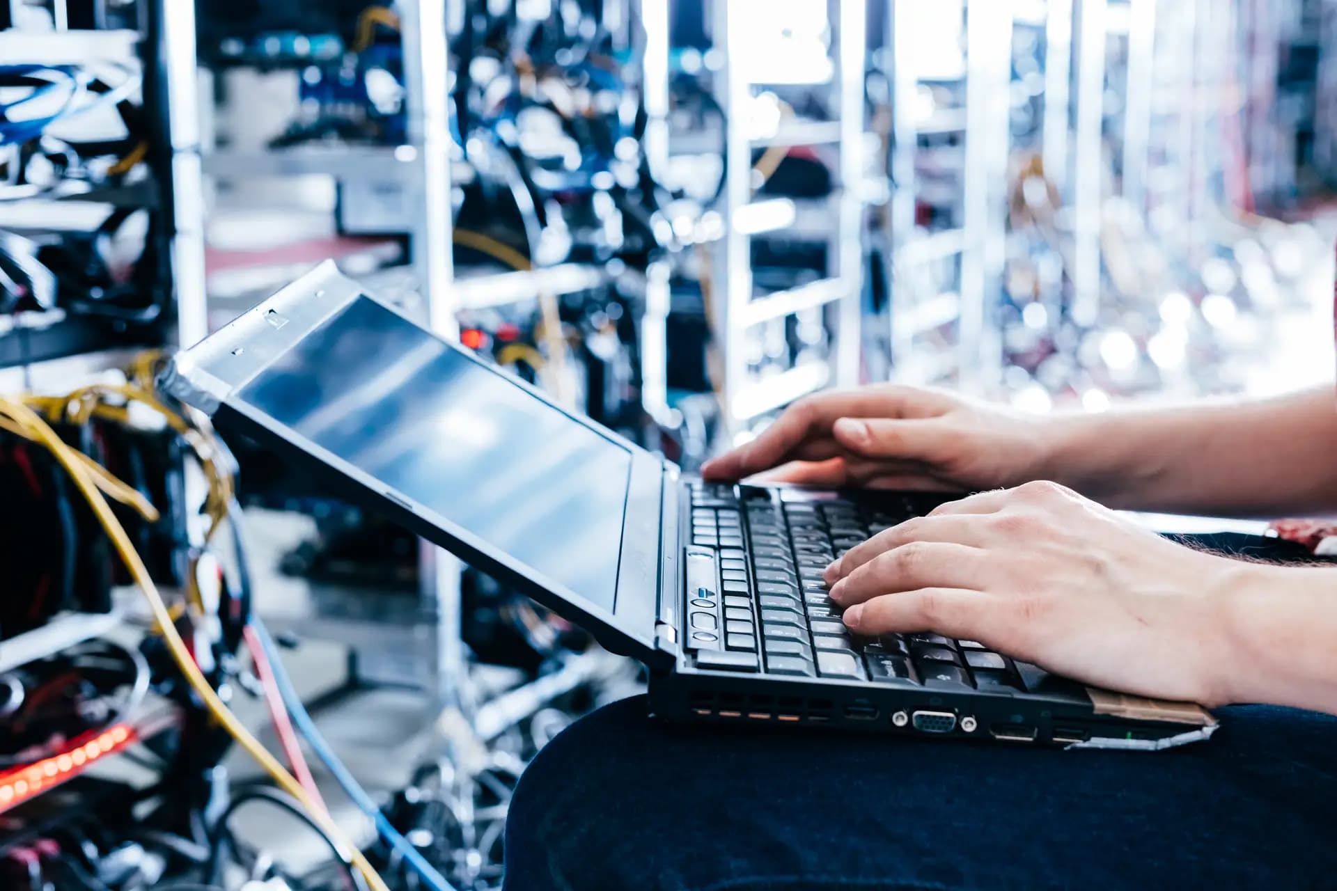 Hände tippen auf einem Laptop vor blau leuchtenden Server-Racks — Sinnbild für Performance-Tuning und Core Web Vitals